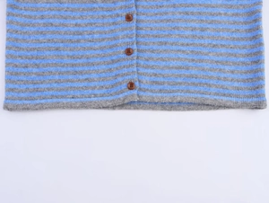 Detail of blue and grey striped knit cardigan featuring textured fabric and brown buttons