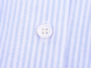 Macro shot of vertical light blue stripes fabric and white button on a crop shirt