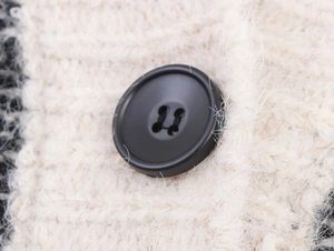 Gros plan sur le bouton noir et la texture en maille torsadée du gilet pour femme