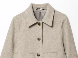 Close-up of light oat wool jacket featuring classic lapels and textured tortoise buttons
