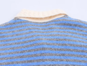 Detailed view of striped knit cardigan featuring a textured cream polo collar and blue fabric