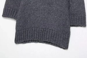 Detail of dark grey chunky knit sweater showing rib-knit hem and thick woven texture
