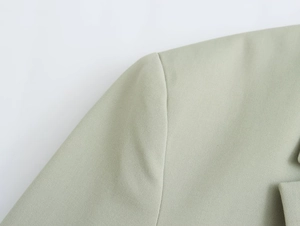 Détail des coutures d'épaule structurées sur une veste blazer verte à coupe droite