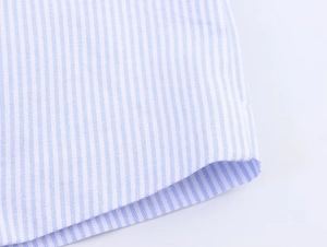 Detailed macro view of the light blue and white pinstripe cotton fabric on the shirt sleeve