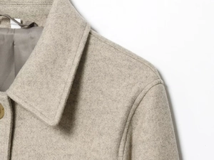Detailed macro view of the lapel and thick wool fabric texture of a beige cropped jacket