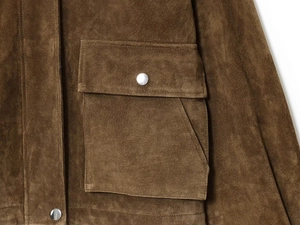Detailed macro view of brown suede jacket pocket featuring a silver snap button