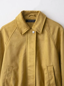 Detail of mustard yellow suede flight jacket featuring a lapel collar and silver metal button