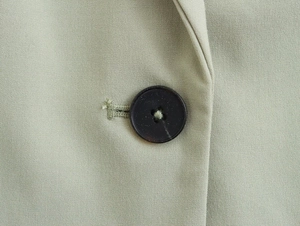 Détail du bouton en résine marron foncé et texture sergé d'un blazer vert clair