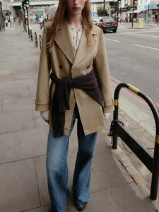 Street style shot of a mid-length faux suede trench coat with double-breasted buttons