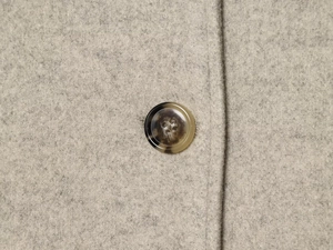 Macro shot of faux tortoise shell button on light gray wool blend cropped jacket