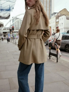 Outdoor shot showing the back tailoring and waist belt of this khaki suede effect trench coat