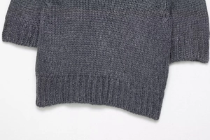 Close-up of chunky dark grey knit sweater showing detailed texture and ribbed cuffs