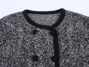 Dettaglio dello scollo rotondo e bordi neri su cardigan in tweed con bottoni neri