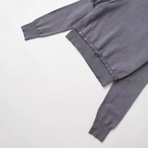Women's grey knitted sweater featuring decorative buttons and ribbed cuffs on white background