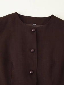 Detail of round neck brown vest vest with fabric covered buttons and textured finish