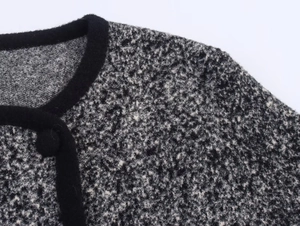 Dettaglio del cardigan in tweed bianco e nero con bordo in velluto e bottone rivestito