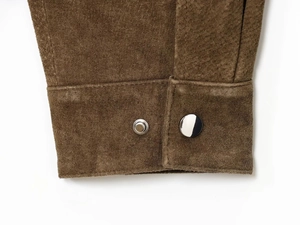 Detailed close-up of brown suede leather jacket with silver metal snap buttons