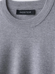 Close-up of gray ribbed knit sweater neckline with a black woven brand label
