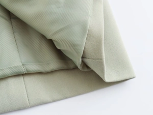 Vue détaillée de la texture du blazer vert sauge et de la doublure lisse avec double couture