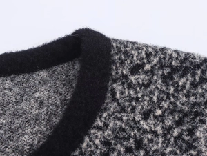 Dettaglio dello scollo del cardigan in maglia bianco e nero con bordo nero liscio