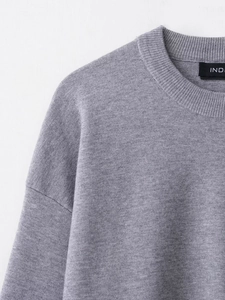 Detail view of the ribbed round neckline and shoulder seam on this gray knit sweater