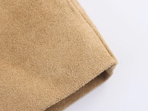 Close-up detail of smooth khaki faux suede fabric texture and neat stitching on long coat