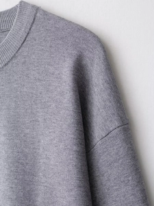 Detail of grey ribbed knit sweater showing high-quality fabric texture and stitching