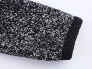 Dettaglio del polsino in maglia di tweed grigio con bordo in tessuto nero nel cardigan