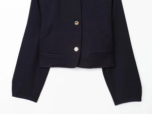 Gros plan du blazer bleu marine avec boutons dorés métalliques et poches passepoilées