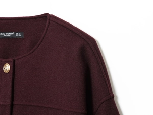 Detail of round neckline on burgundy bomber jacket with gold embossed metal button