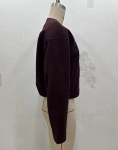 Detail der burgunderroten Kurzjacke mit goldfarbenen Knöpfen auf beigefarbener Schaufensterpuppe