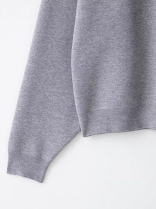Close-up of grey ribbed knit sweater sleeve showing fine stitching and soft fabric