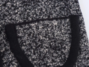 Dettaglio ravvicinato del tessuto in maglia tweed e tasca con bordo nero a contrasto