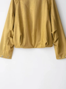 Detail view of mustard yellow suede jacket featuring gathered hem and metallic snap buttons