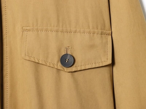 Dettaglio della giacca in twill kaki con cuciture sulla tasca a patta con bottone
