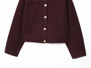 Close-up of golden embossed buttons and pockets on a burgundy wool bomber jacket