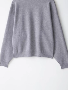 Detailed close-up of ribbed cuffs and hem on a casual grey knit sweater