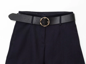 Gros plan sur la boucle dorée du ceinture en cuir avec pantalon de costume noir