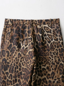 Detailed close-up of leopard print fabric texture and belt loops on high waist trousers