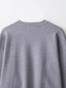 Detail shot of grey ribbed knit sweater neckband and drop shoulder seam craftsmanship