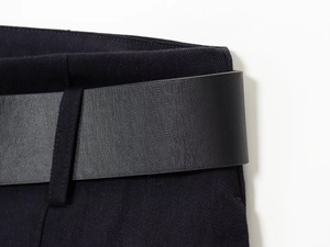 Vue détaillée d'une ceinture en cuir noir sur un pantalon en tissu sergé bleu marine