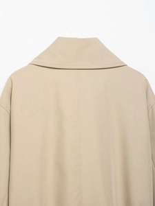 Detailed close-up showing the fine twill texture and stitching on a beige trench coat back