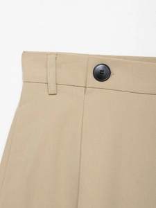 Macro shot of khaki trousers waist detailing featuring black button and fine stitching