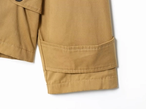 Dettaglio ravvicinato della giacca in twill kaki con doppia cucitura e bottone