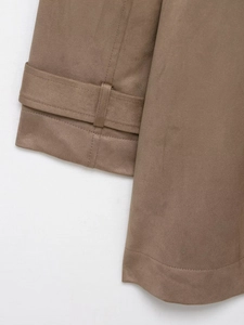 Detail of brown faux suede trench coat cuff featuring a decorative strap and stitching