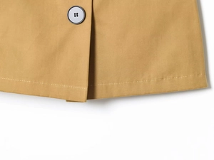 Dettaglio del tessuto in twill di cotone color cammello con bottone nero e doppia cucitura