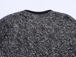 Dettaglio del girocollo e del bordo nero su cardigan in maglia testurizzata bianco e nero