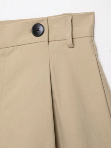 Close-up of khaki trousers waist with black button and pleated twill fabric detail