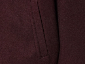 Close-up of the burgundy bomber jacket showing the textured wool fabric and pocket seam