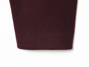 Close-up of deep burgundy soft fabric texture and golden button on bomber jacket